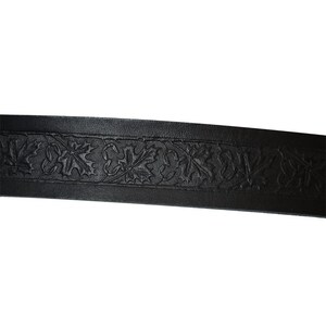 Op de afbeelding: Zwarte leren riem met een decoratief reli&euml;fpatroon van bladeren.