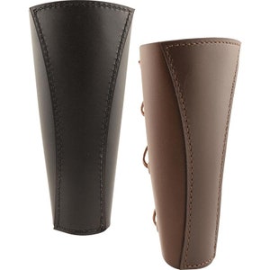 May include: Two leather arm guards, one black and one brown, with laces for fastening. The guards are made of thick leather and have a stitched design.