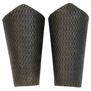 May include: A pair of black leather arm guards with a scale-like pattern. The guards are made of thick leather and have a slightly curved shape.