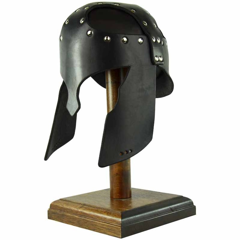 May include: A black leather helmet with a metal studded design. The helmet is on a wooden display stand.