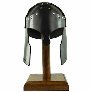 May include: A black leather helmet with a studded design, displayed on a wooden stand. The helmet has a rounded top and a pointed chin guard.