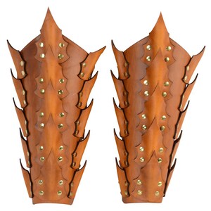 Op de afbeelding: Een paar bruine leren armbeschermers met een stekelig ontwerp en gouden metalen accenten.