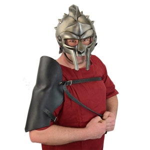 May include: A silver gladiator helmet with a spiked crest and a black leather arm guard. The helmet has a face mask with a raised nose and eye holes.