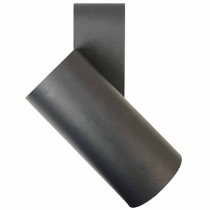 May include: A black leather belt loop with a cylindrical shape. The loop is designed to hold a belt and is made of a durable material.