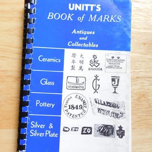 May include: A spiral-bound book titled "UNITT'S BOOK of MARKS" with a blue cover and white text. The book is open to a page with various antique and collectable marks. Categories include Ceramics, Glass, Pottery, and Silver & Silver Plate.