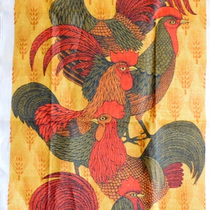 May include: A yellow tea towel with a pattern of wheat stalks and four red, green, and brown roosters. The roosters are in various positions, some with their wings spread and others with their heads turned.