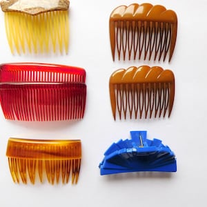May include: Assortment of six hair combs in various colours and styles.  The combs are made of plastic and have different tooth patterns.  There is also a blue plastic hair clip.