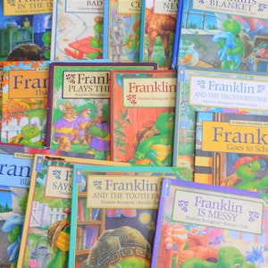 Puede incluir: Una colección de libros infantiles con el personaje Franklin la Tortuga. Los libros tienen portadas coloridas con ilustraciones de Franklin en varios escenarios. Los títulos incluyen "Franklin juega" y "Franklin va a la escuela."