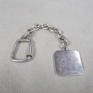 May include: A silver keychain with a square tag and a lobster clasp.