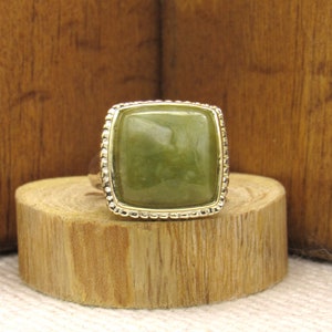 May include: A gold ring with a large, rectangular, green gemstone set in a beaded frame.