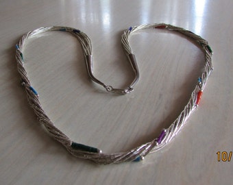 May include: A silver necklace with multiple strands and colorful gemstone accents. The necklace is twisted and has a heart shape.