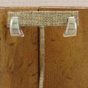 May include: A pair of silver earrings with a geometric design featuring white opal stones.