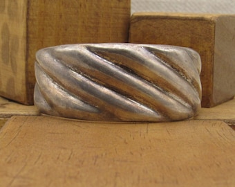 May include: A silver bracelet with a twisted, rope-like design. The bracelet is made of a smooth, polished metal and has a simple, elegant style.