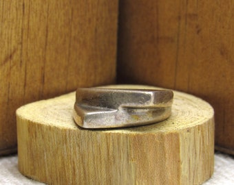 May include: A silver ring with a unique, angular design. The ring is sitting on a wooden surface.