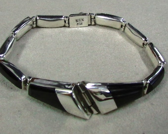 May include: A silver bracelet with black onyx accents. The bracelet has a clasp with the inscription "MEX 925".