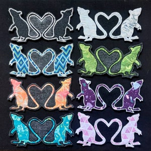 May include: Ten pairs of felt mouse appliques in various colours and patterns, each pair is in a heart shape with their tails intertwined.