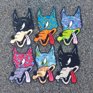 May include: Six embroidered patches featuring cartoon wolf faces with different colored backgrounds and patterns. The wolf faces have black eyes, white teeth, and pink tongues sticking out. The patches are made of fabric and have a stitched edge.