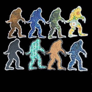 Puede incluir: Ocho parches de tela que representan la silueta de un Bigfoot. Cada parche presenta un patrón diferente, incluyendo diseños de galaxia, paisley y florales.