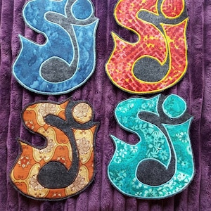 May include: Four fabric patches in the shape of the letter "S" with different patterns. The patches are blue, red, orange, and green. Each patch has a gray felt center.