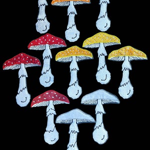 Puede incluir: Diez parches bordados con forma de hongo en varios tonos de rojo, naranja y amarillo. Los hongos tienen tallos blancos y están delineados en negro.