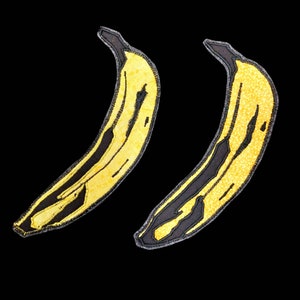 May include: Two yellow bananas with black outlines, stitched together, against a black background.