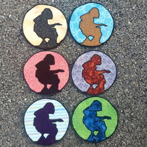 Peut inclure: Six dessous-de-verre ronds en tissu avec une silhouette d'une personne assise sur les toilettes. Chaque dessous-de-verre a un motif et une couleur de fond différents, y compris le jaune, le bleu, le rose, le violet, le vert et le bleu.