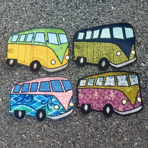 May include: Four colorful fabric appliques of vintage Volkswagen vans. Each van is a different color and pattern: yellow with green polka dots, green with yellow stripes, purple with pink and white floral print, and blue with pink and white swirls.