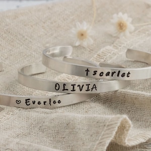 May include: Three silver bracelets with the names "Everlee", "Olivia", and "t'scarlet" engraved on them.