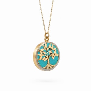 Peut inclure: Un collier en or avec un pendentif circulaire orné d'un motif d'arbre. L'arbre est représenté en or sur un fond turquoise vif, encadré par une fine bordure métallique. Le pendentif est suspendu à une fine chaîne en or à petits maillons.