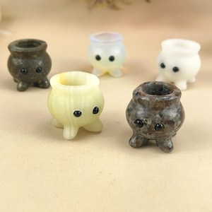 Può includere: Cinque piccole figurine a forma di calderone scolpite a mano con volti carini. I calderoni sono fatti di diversi materiali, tra cui pietra bianca, marrone e grigia.