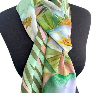 Puede incluir: Una bufanda de seda verde y blanca con un patr&oacute;n floral y geom&eacute;trico. La bufanda est&aacute; atada alrededor del cuello de un maniqu&iacute;.