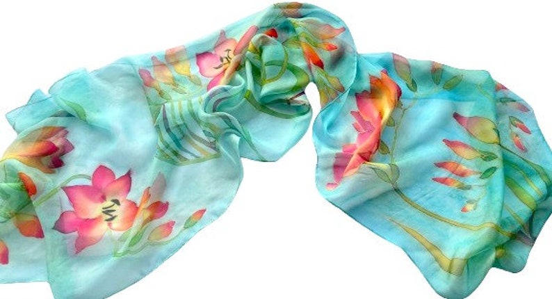 Pode incluir: Um len&ccedil;o leve e semitransparente em azul turquesa brilhante. O tecido apresenta um padr&atilde;o floral pintado &agrave; m&atilde;o com flores vibrantes em tons de rosa, laranja e amarelo, juntamente com caules e folhas verdes por toda a superf&iacute;cie.