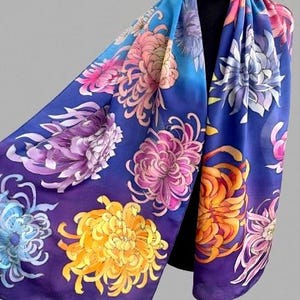 May include: A silk scarf with a blue background and a floral pattern of chrysanthemums in shades of pink, purple, yellow, and orange.