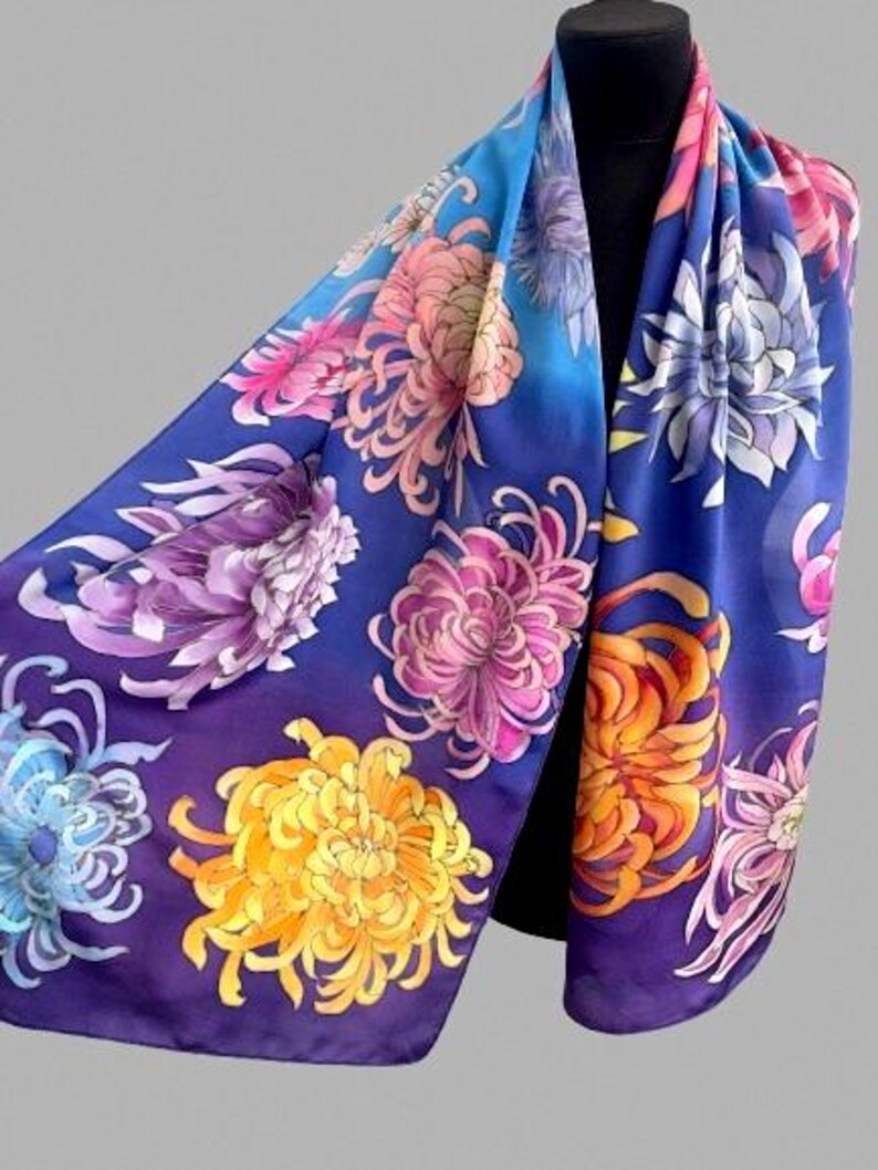 May include: A silk scarf with a blue background and a floral pattern of chrysanthemums in shades of pink, purple, yellow, and orange.