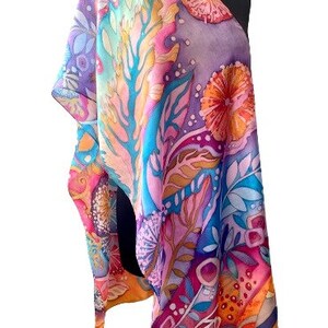 May include: A colorful silk scarf with a floral pattern in shades of pink, blue, yellow, and orange. The scarf is draped over a mannequin's shoulders.