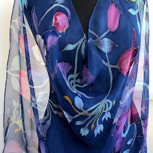 May include: A navy blue silk scarf with a floral pattern in shades of pink, purple, blue, and yellow. The flowers are stylized and resemble tulips.