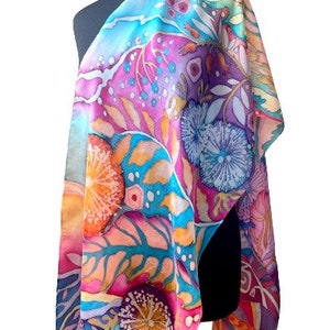 May include: A colorful silk scarf with a floral pattern in shades of pink, blue, yellow, and orange. The scarf features a variety of flowers and leaves, and the design is reminiscent of a garden.