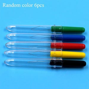 May include: A set of five needle threaders with clear plastic protective caps and colored handles in green, blue, red, yellow, and black. Each tool features a thin wire loop for threading needles. The text Random color 6pcs is visible.
