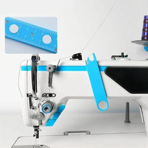 Puede incluir: Una máquina de coser industrial blanca con detalles azules y una herramienta de metal azul unida al lateral. Un recuadro muestra un primer plano de la herramienta azul, una regla plana con marcas de 0 a 20 cm y dos aberturas circulares.