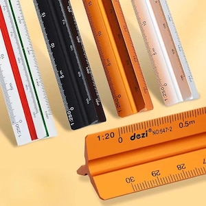 Puede incluir: Una colección de reglas de escala arquitectónica triangulares en blanco, negro, naranja y plata. Cada regla presenta marcas de medición precisas, proporciones como 1:250 y 1:20, y la marca dezi con el número de modelo 547-2 en la regla naranja.