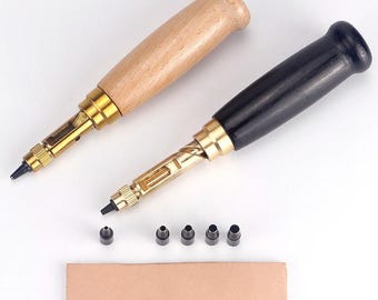 May include: Two leather hole punch tools with brass mechanisms and wooden handles, one light brown and one black. The set includes five interchangeable black metal punch tips and a rectangular piece of tan leather with six punched holes of varying sizes.