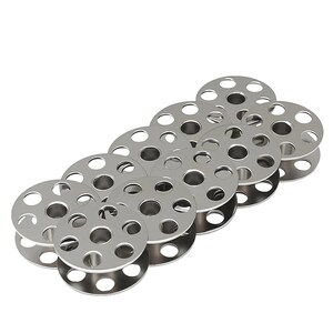 May include: A collection of ten silver-colored metal sewing machine bobbins arranged in a staggered formation. Each circular bobbin features a central hole and a series of evenly spaced circular cutouts around the perimeter of the flat discs.