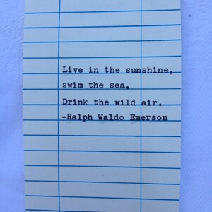 Peut inclure: Une carte de biblioth&egrave;que vintage avec des lignes bleues et du texte. La carte pr&eacute;sente la citation "Live in the sunshine, swim the sea, Drink the wild air." de Ralph Waldo Emerson. La carte comporte des espaces pour "Date Due" et "Borrower's Name".