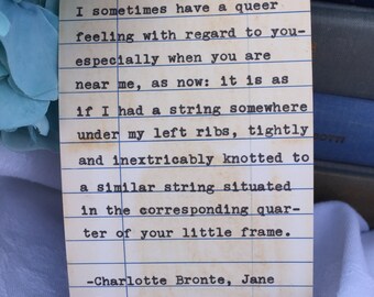 Puede incluir: Una ficha de biblioteca de estilo vintage en papel envejecido y manchado con el texto impreso: I sometimes have a queer feeling with regard to you-especially when you are near me, as now: it is as if I had a string somewhere under my left ribs, tightly and inextricably knotted to a similar string situated in the corresponding quarter of your little frame. -Charlotte Bronte, Jane Eyre.