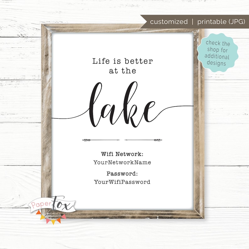 May include: A printable sign with the text "Life is better at the lake" in black cursive font. Below the text is a wifi network name and password. The sign is framed in a light brown frame.