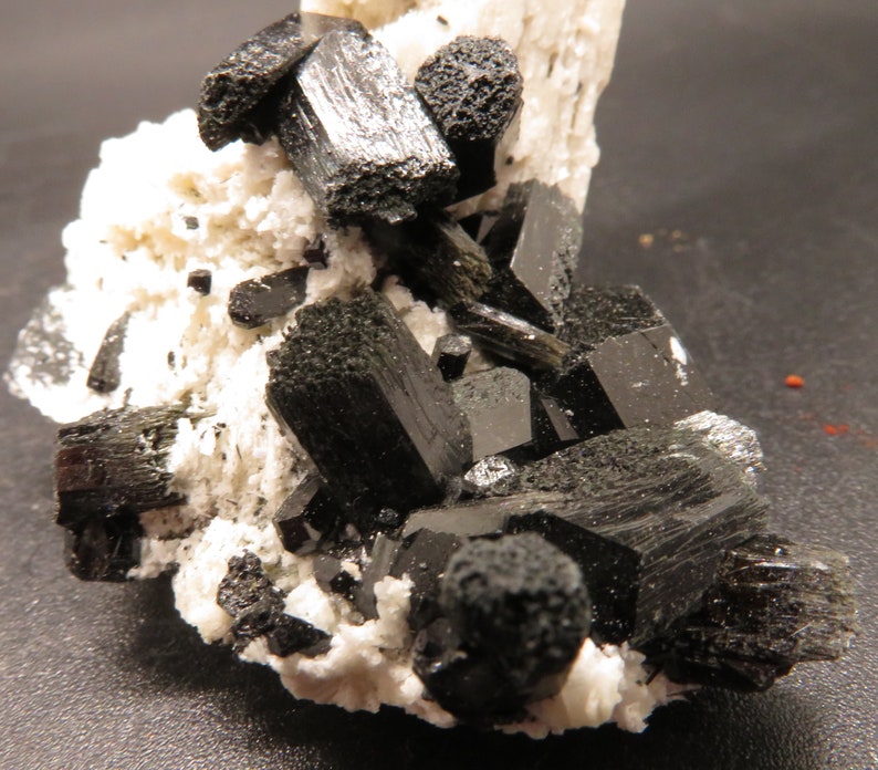May include: A cluster of black schorl crystals on a white albite matrix. The crystals are sharp and well-formed, with a glassy luster.