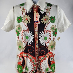 Könnte beinhalten: Ein weißes, kurzärmeliges Hemd mit Knöpfen und einem schwarz-weißen Blumenmuster. Das Hemd hat einen Kragen und eine Knopfleiste. Das Hemd hat ein Etikett mit der Aufschrift "Kodee".