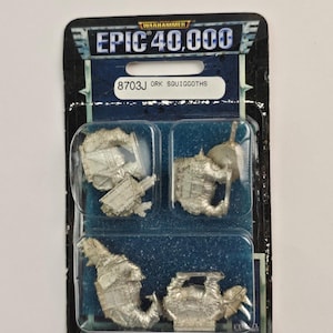 May include: A packaged set of Warhammer Epic 40,000 Ork Squiggoths miniatures. The package is black with blue accents and the text "EPIC 40,000" and "8703J ORK SQUIGGOTHS". The miniatures are silver and in a clear plastic blister pack.