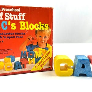 May include: A vintage Mattel Tuff Stuff ABC's Blocks toy box with a red, white, and blue color scheme. The box features a young child holding letter blocks that spell "MOM". The box also includes the text "30 rugged letter blocks for stack'n spell fun! Ages 1 1/2 to 5. No. 4383" and "3-Year Limited Warranty". The image also shows four letter blocks spelling "CAT" in yellow, blue, and red.