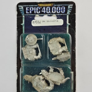 May include: A Warhammer Epic 40,000 miniature set, DRK Squiggoths, in a clear plastic blister pack. The package features the Warhammer logo and product information. The set includes several unpainted metal miniatures.